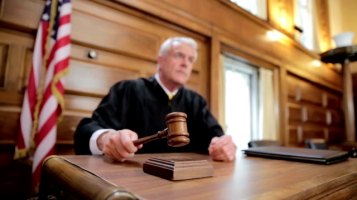 Judge banging gavel on bench in courtroom. CU, slow motion.